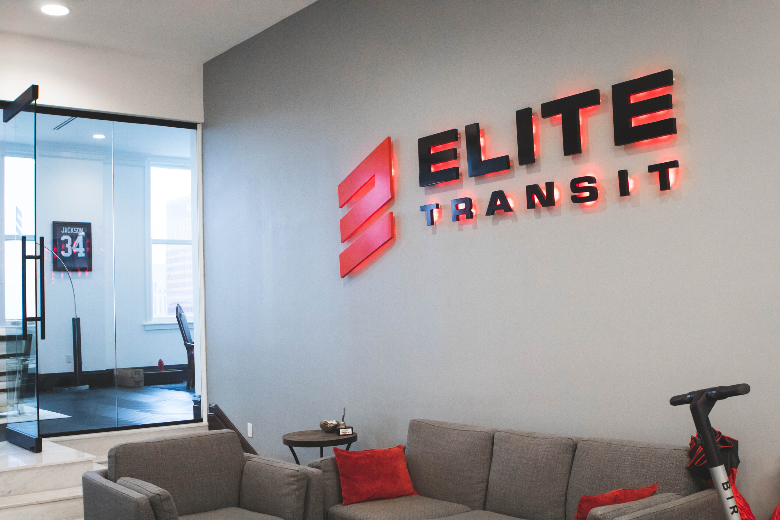ELITE Transit Pittsburgh lobby entrance with black and red sign, red back lights, above a grey couch