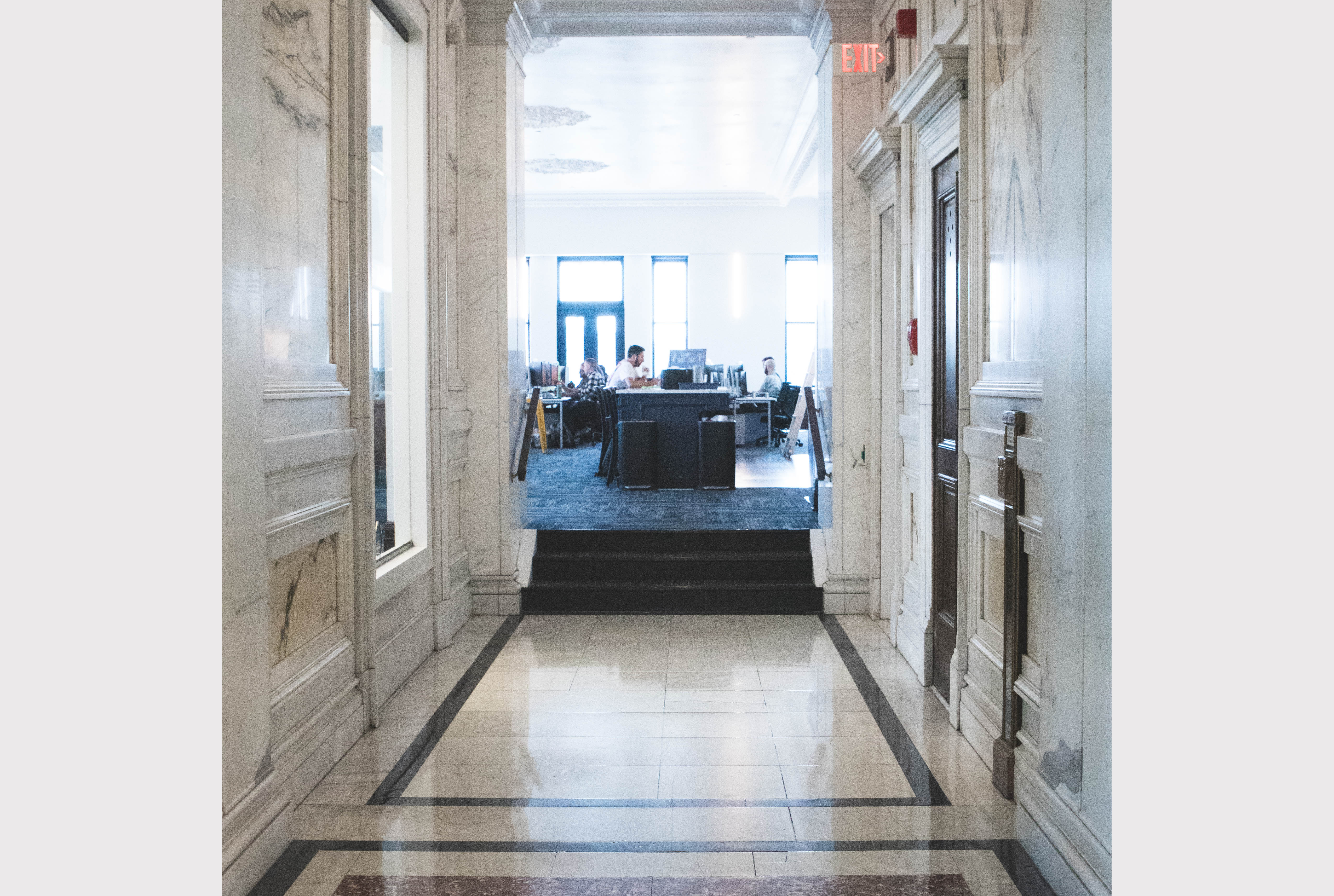 Pale marble hallway looking into the kitchen area in the ELITE Transit Solutions' Pittsburgh office, inside the Frick Building.